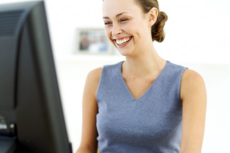 Young Woman Sitting in Front of a Computer and Laughing